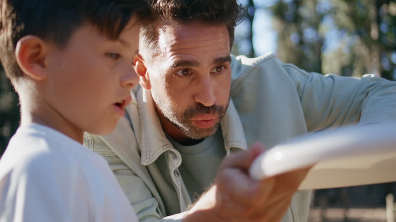 Father teaching son throwing frisbee disc at sunny forest closeup. Happy family