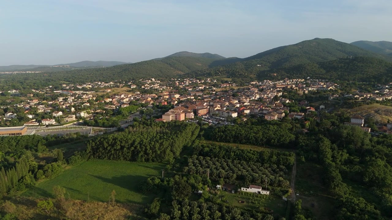 Paesaggio panoramico ripreso da drone di una città mediterranea circondata da campi verdi e colline