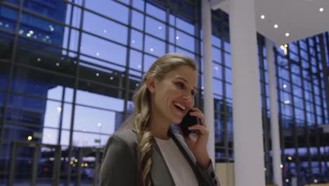 Businesswoman-talking-on-mobile-phone-in-the-lobby-at-office-4k