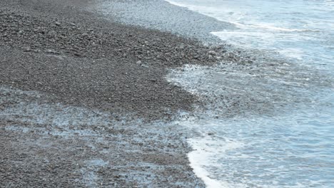 atlantic ocean waves washing small pebbles on tenerife beach