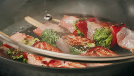 cooking salmon skewers with broccoli and peppers