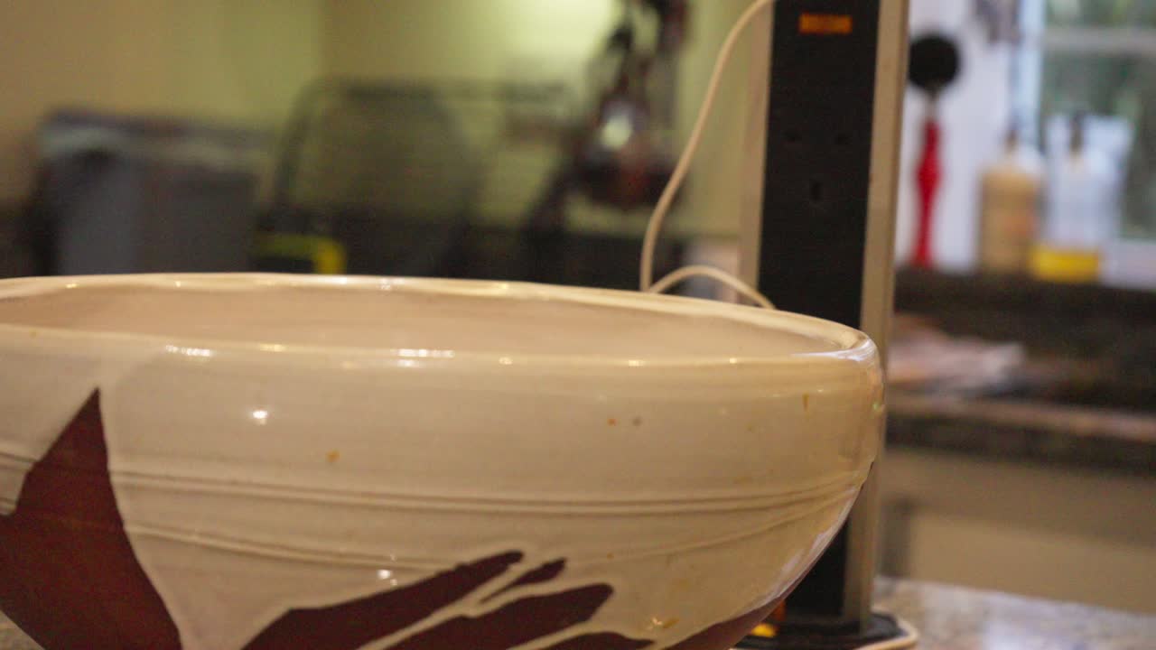 A close-up of green dish soap bottle and woman's hand reaching for cleaning task