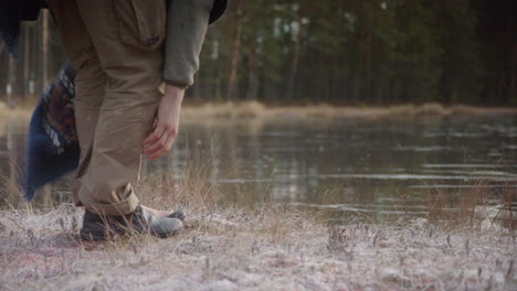 TRACKING-shot-of-an-ice-bather-removing-shoes-and-socks-in-front-of-frozen-lake