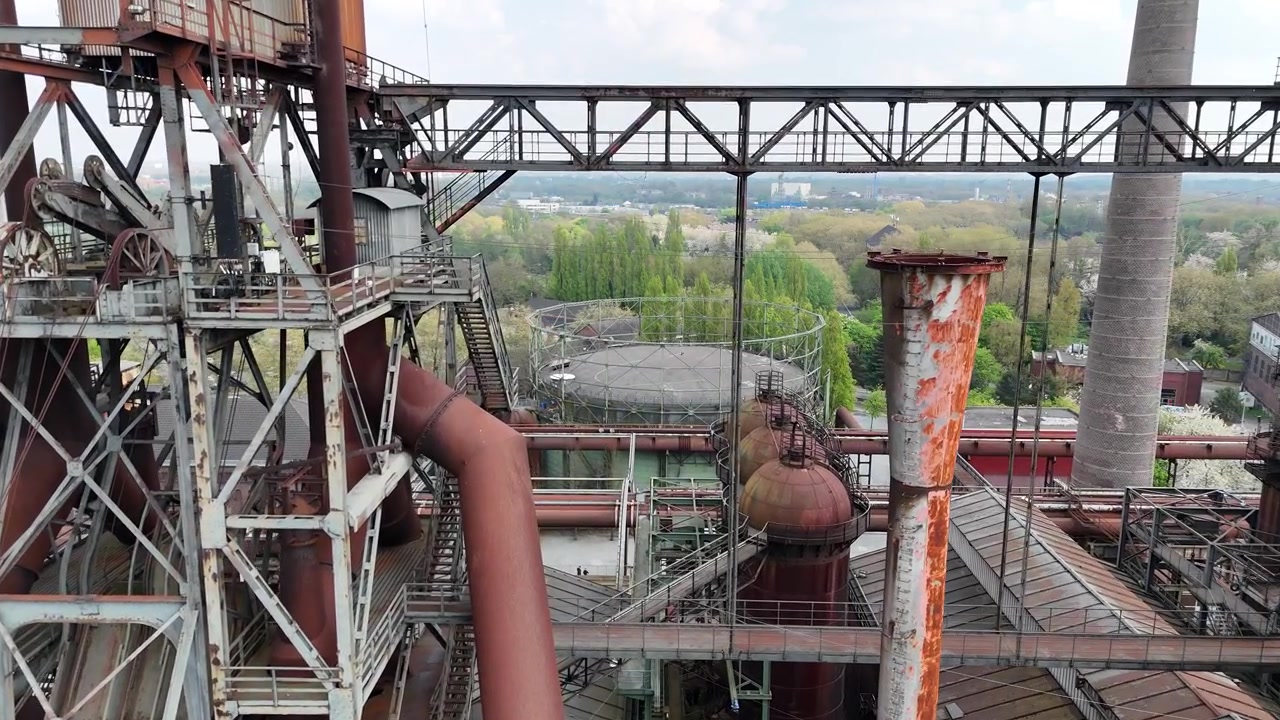 Paralelní pohyb dronu přes pece s květy a obřími trubkami.