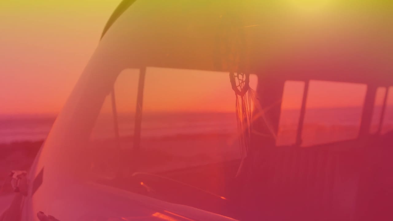 꿈을 잡는 사람이 캠퍼 밴으로 움직이는 애니메이션. 배경에는 해가 지는 노란색에서 빨간색의 색조가 있습니다.