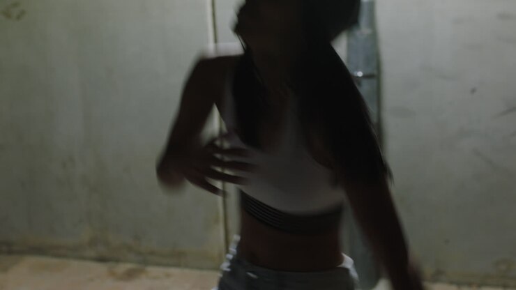 donna danzante giovane ballerina di strada donna che pratica movimenti di danza moderna freestyle in città di notte indossando un cappello