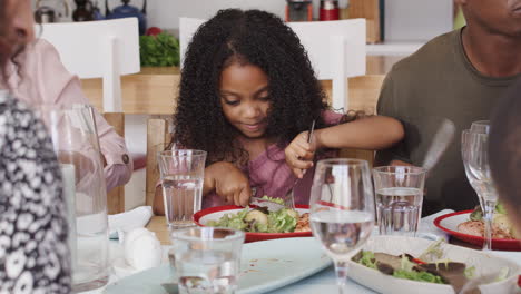 multi-generation family sitting around table at home enjoying meal together
