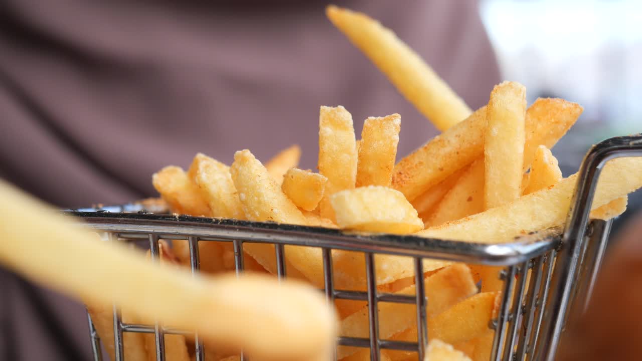 Close-up of golden-brown french fries in a metal basket