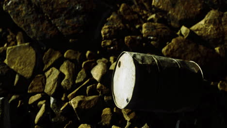 spotlight reveals an old barrel among rocky terrain at night