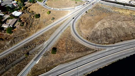 Aerial-overhead-approach-hyperlapse-shot-of-Cars-driving-on-the-Highway-1-and-Yellowhead-Intersection-in-Kamloops,-Thompson-Okanagan-in-British-Columbia-Canada-in-a-desert-environment