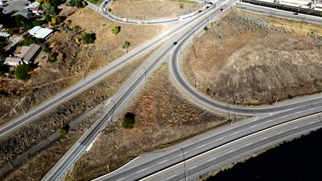 aerial overhead approach hyperlapse shot of cars driving on the highway 1 and yellowhead intersection in kamloops, thompson okanagan in british columbia canada in a desert environment