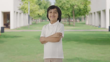 portrait of happy indian boy standing crossed hands in park