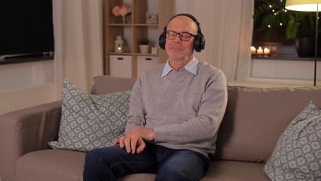 senior man with tablet pc and headphones at home