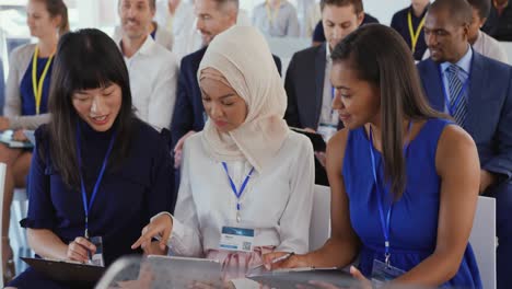 women in the audience at a business seminar talking