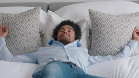 hombre feliz saltando en la cama en la habitación del hotel descansando después de un exitoso viaje de viaje sonriendo disfrutando de la libertad de estilo de vida independiente