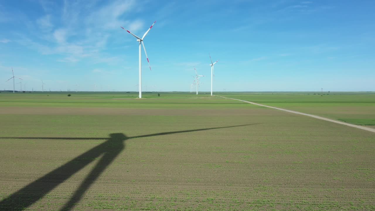 Long shadow of windmill, large wind power turbines spinning to generating clean, green, renewable energy