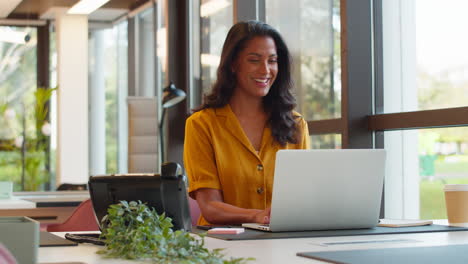 Mujer-De-Negocios-Madura-Trabajando-En-Una-Computadora-Portátil-En-El-Escritorio-De-La-Oficina-Haciendo-Una-Pausa-Para-Mirar-Por-La-Ventana