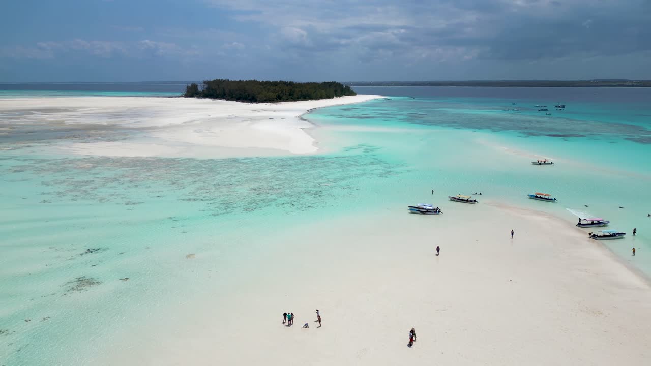 Mnemba island of Zanzibar,Tanzania Africa with snorkeling tour boats and visitors on the sandy beach, Aerial dolly left shot