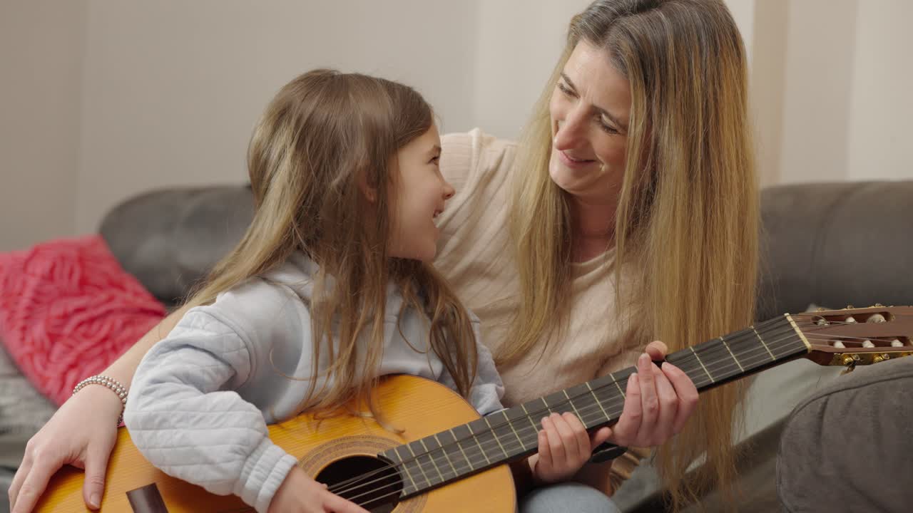 Mother and daughter learning to play guitar together