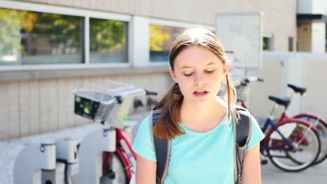 Portrait-of-irritated-fifteen-year-old-girl-by-city-bikes