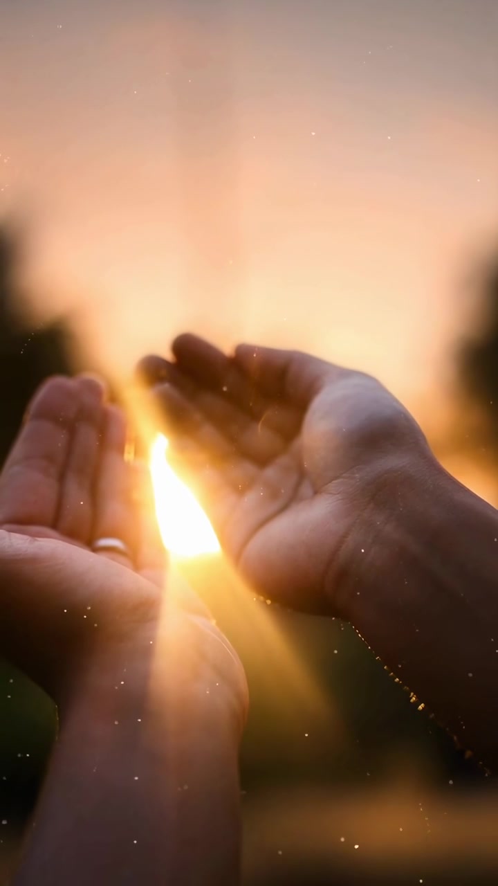 Persona con le mani alzate verso un tramonto dorato