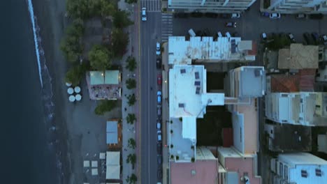 aerial top down, bird's eye view of coastal road of kalamata, navarinou street, sea and sandy beach on the frame, low traffic on the road 4k