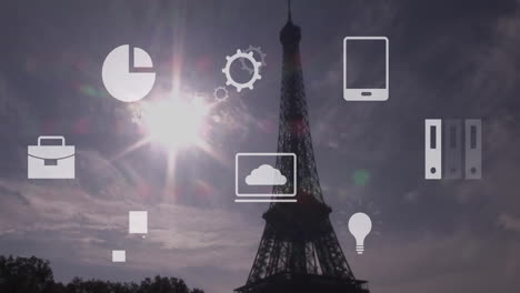 animación de múltiples iconos sobre la torre eiffel contra el sol y el cielo nublado.
