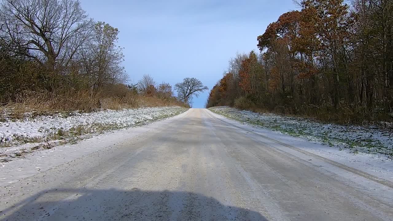 Point of View out of the drivers window; Driving past farms and fields in rural Illinois USA on snow.