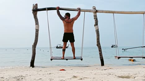 hombre balanceándose en un columpio en la playa de tailandia