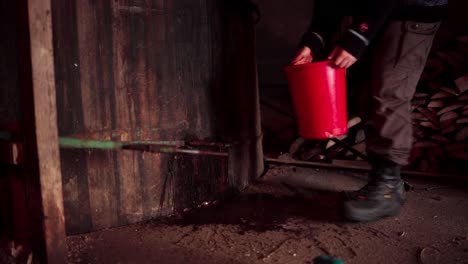 man pours water onto steel bar before cutting with angle grinder inside the barn