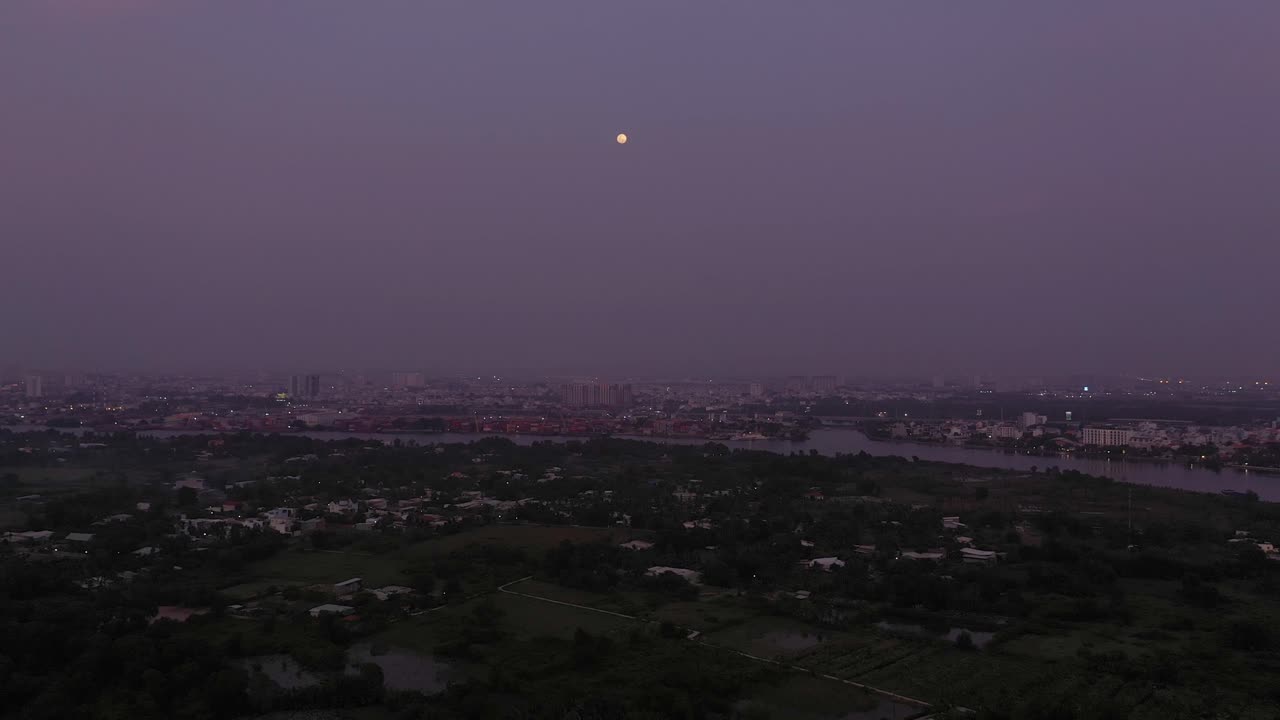 Pemandangan udara Sungai Saigon saat senja dengan cahaya alami dan buatan yang mengarah ke bulan purnama.