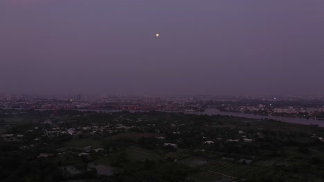 Vista-Aérea-Del-Río-Saigón-En-El-Crepúsculo-Con-Luz-Ambiental-Y-Artificial-Mirando-Hacia-La-Luna-Llena