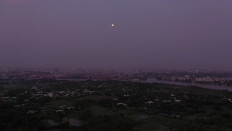 aerial view of saigon river in the twilight with ambient and artificial light looking towards full moon