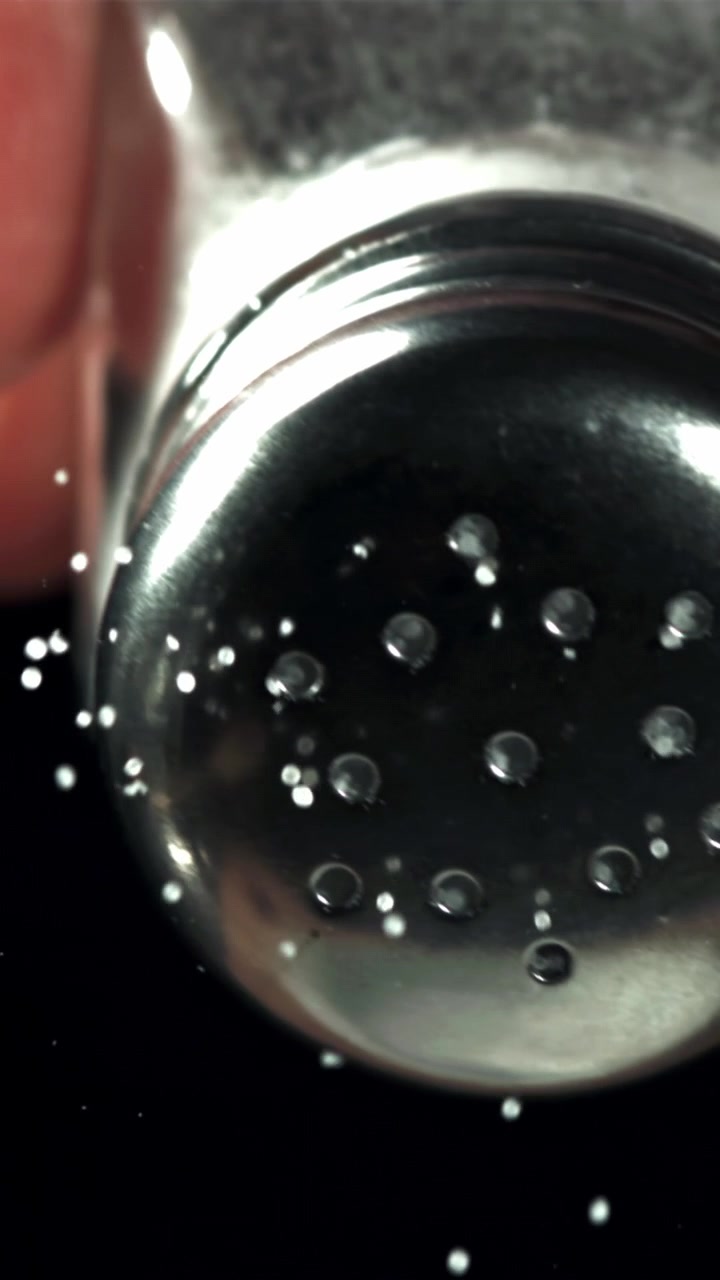 Macro di sale che cade da una saliera su sfondo nero