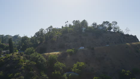 Toma-De-Seguimiento-De-Un-Camión-De-Reparto-Conduciendo-Por-Una-Carretera-Montañosa-Ventosa-Ubicada-En-Las-Colinas-De-Hollywood,-En-El-Sur-De-California