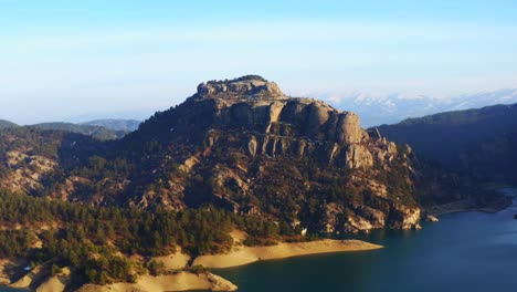 Aerial-view-of-Rock-mass,-river-flows-at-the-foot-of-the-rocky-mountains,-sunny-day