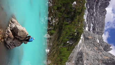 hombre escalando un montículo rocoso en las aguas glaciares azules del lago sorapis