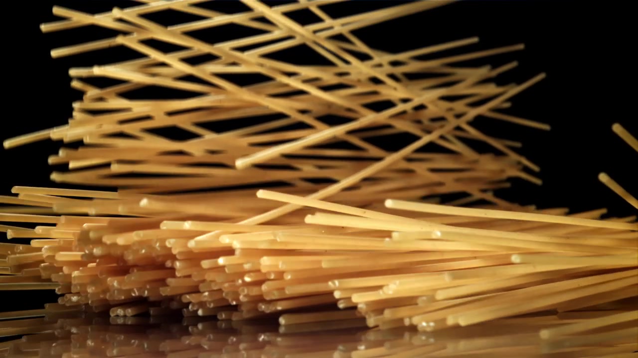 Spaghetti crudi che cadono al rallentatore su sfondo nero