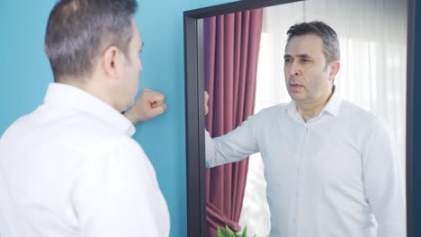 Depressed-man-looking-at-himself-in-the-mirror-and-helpless.