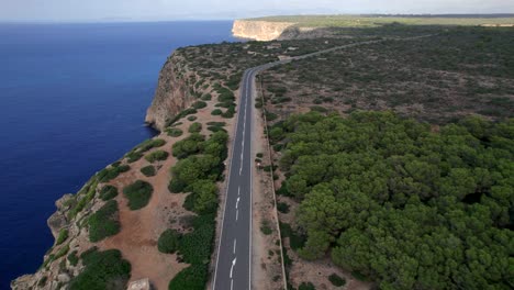 along empty coastal road in badia de palma, spain, forward aerial