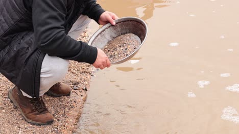 man panning for gold in muddy water