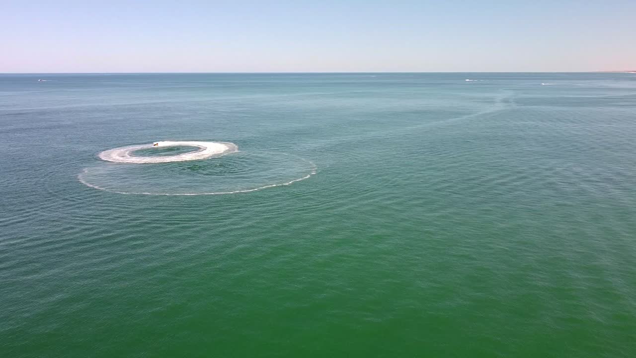 크리클에서 경주하는 제트스키 라이더를 향한 공중 전망은 웨이크 패턴을 남니다.