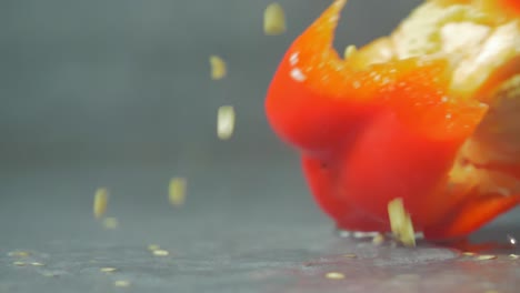 half-red-bell-pepper-falling-on-water,-seeds-explosion