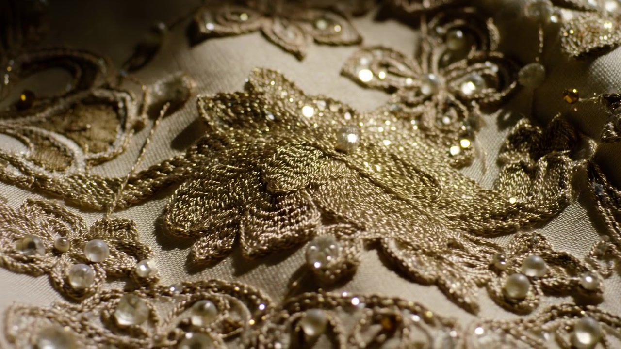 Primo piano di ricamo dorato rivela pizzo ornato, paillettes sparse, perle, applicazione a strati e scintillio.