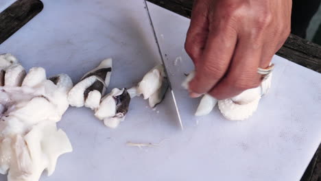 una mujer con un cuchillo de cocina corta los tentáculos de calamar.
