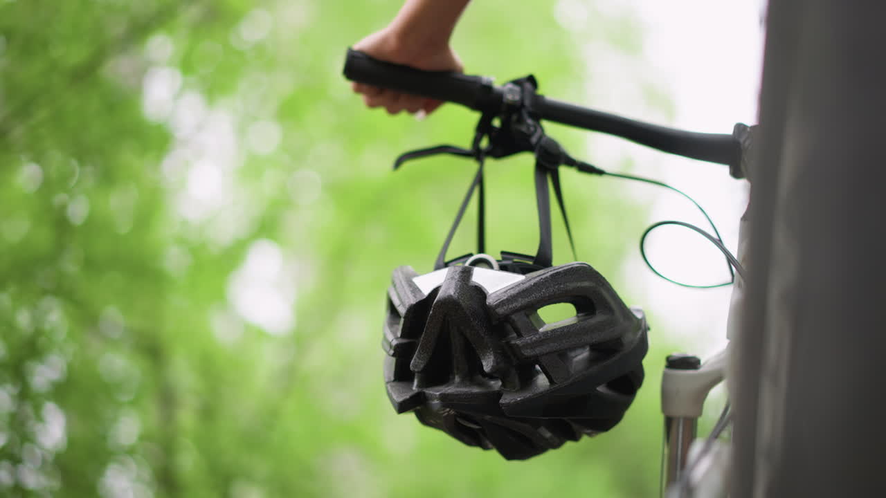 Closeup Of Handlebars With Helmet, Captured Moment Of Helmet Above Bike Handlebars With Greenery Background, Quick Preride Gesture Showing Helmet Suspended Over Bicycle Handles Amid Leafy Scenery