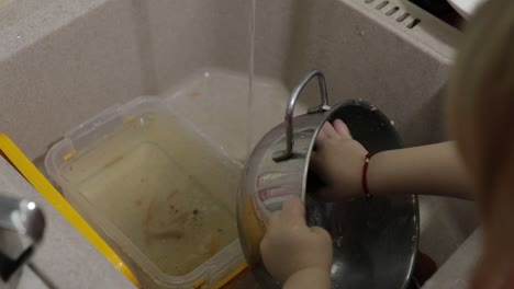 child washing dishes in the kitchen. close up of girls hands