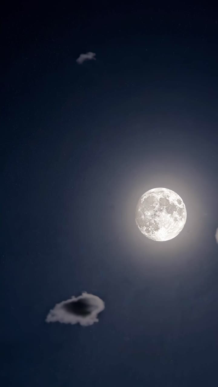 Um vídeo de um céu noturno sereno com uma lua cheia brilhando em meio a nuvens dispersas