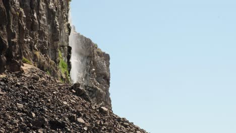 side view as thin waterfall mists down cliff in potholes coulee, wa