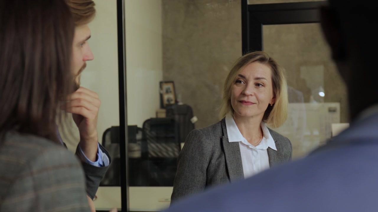 Smilende forretningskvinde engageret i diskussion med kolleger